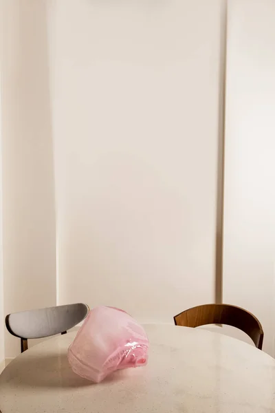 Декоративная розовая фигурка на круглом столе возле деревянных стульев в дневное время — стоковое фото