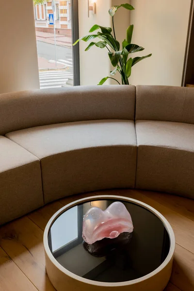 Decorative figurine on round coffee table near sofa and green plant in hotel — Photo de stock