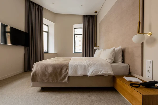 Flat screen on wall near comfortable bed in modern hotel bedroom — Stock Photo