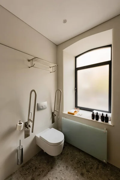 Інтер'єр білої ванної кімнати з туалетом для людей з обмеженими можливостями в готелі — стокове фото
