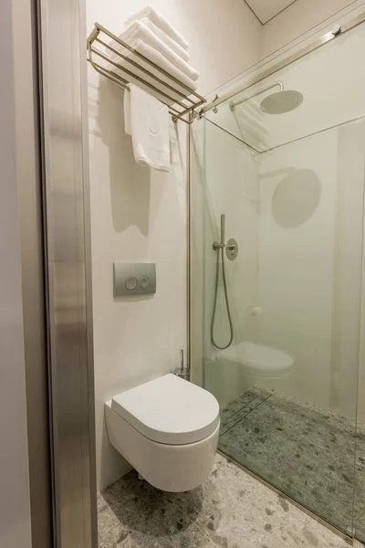 Интерьер современной белой ванной комнаты с белым туалетом возле стеклянной двери и душем — стоковое фото