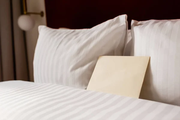 Желтый конверт на белом и чистом постельном белье в номере отеля — стоковое фото