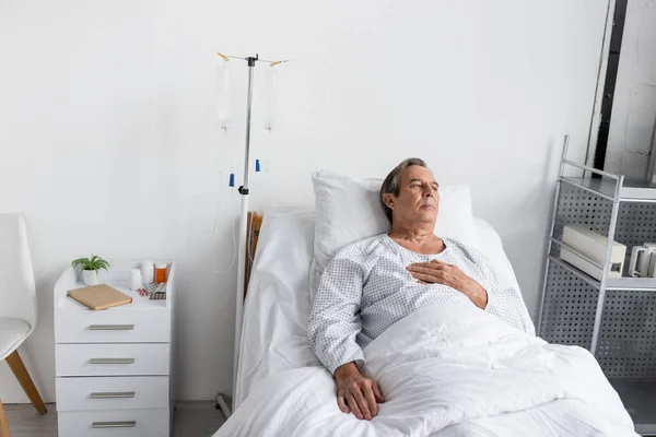 Elderly man lying near intravenous therapy in hospital ward — Stock Photo
