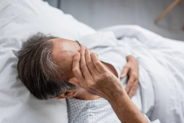 Overhead view of sick elderly man lying on bed in hospital ward — Stock Photo