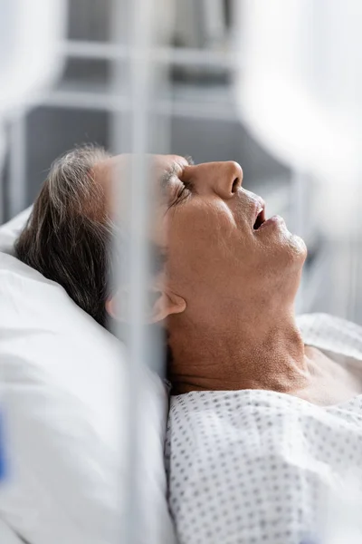 Paziente con i capelli grigi sdraiato sul letto nel reparto ospedaliero — Foto stock