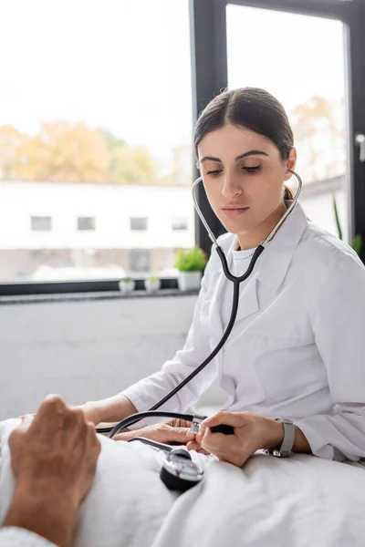 Doctor checking blood pressure of senior patient in hospital — Stock Photo