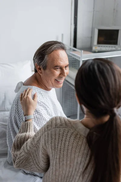 Blurred woman calming smiling senior father in hospital ward — Stock Photo