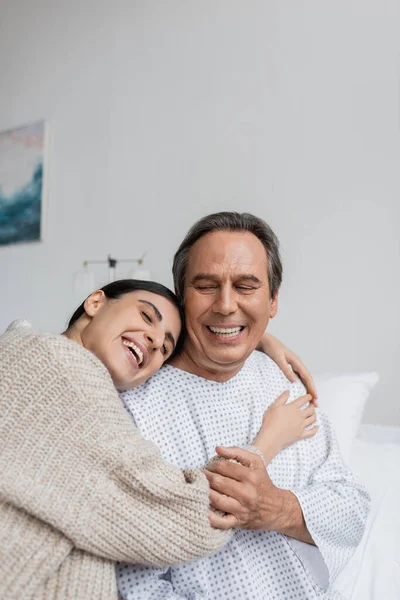 Позитивная дочь обнимает отца в больничном халате — стоковое фото