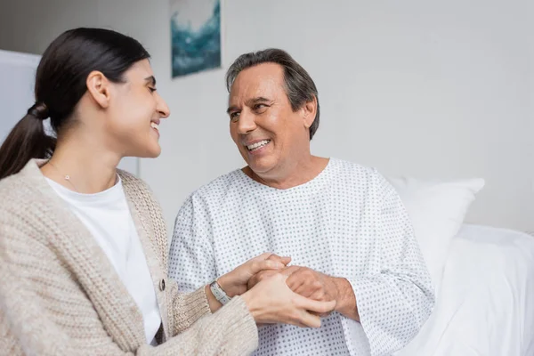Улыбающаяся женщина держит отца за руку в больничном отделении — стоковое фото