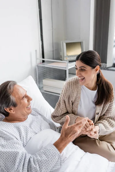 Positive man in patient gown talking to daughter in clinic — Stock Photo