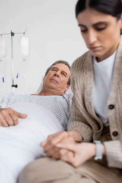 Uomo malato guardando la figlia sconvolta offuscata mentre giaceva sul letto in ospedale — Foto stock