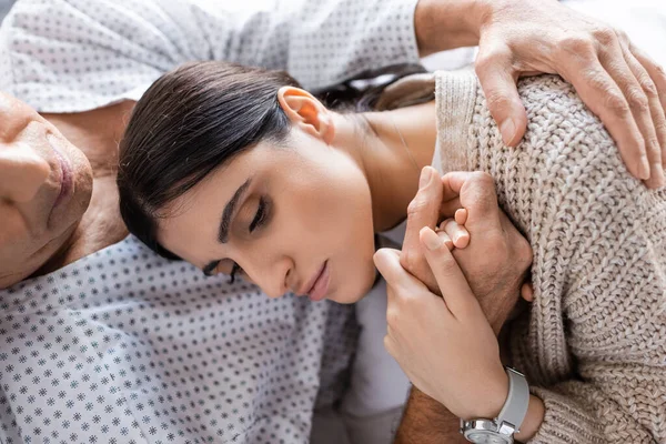 Visão superior da mulher chateada segurando a mão do pai doente no hospital — Fotografia de Stock