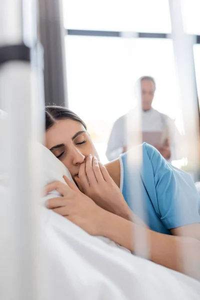 Sad patient lying with closed eyes on bed in hospital ward - foto de stock