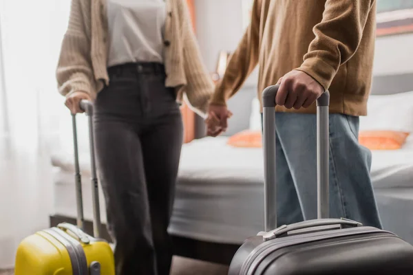 Partial view of blurred couple with luggage holding hands in hotel apartments — Stockfoto