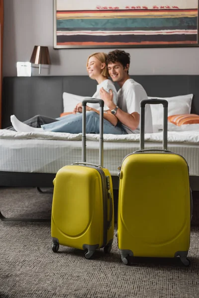 Вибіркова увага до подорожей біля щасливої молодої пари сидить на ліжку готелю на розмитому фоні — стокове фото
