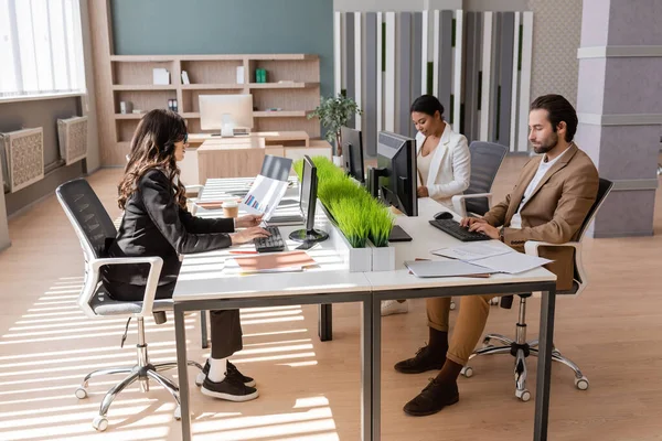 Multiethnic businesspeople working with computers and documents in modern office — Stock Photo