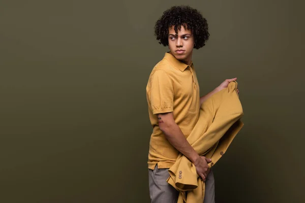 Стильный африканский американец в рубашке в поло, в жёлтой куртке и на оливково-сером фоне — стоковое фото