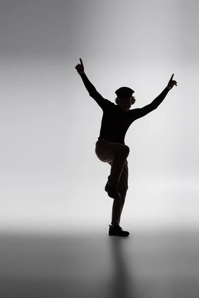 Dark silhouette of african american man posing with raised hands and pointing with fingers on grey background — Stock Photo