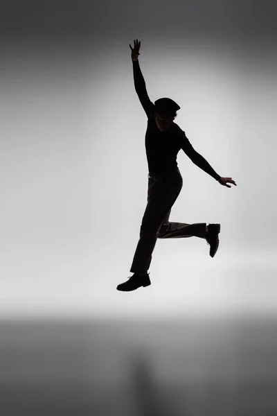 Dark silhouette of young african american man jumping on grey background — Photo de stock