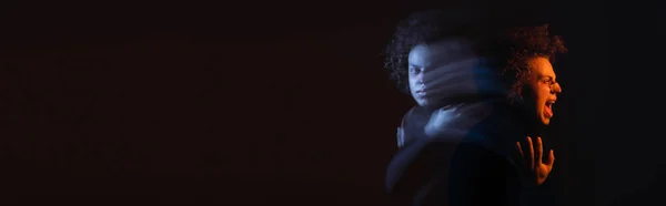 Двойное воздействие раненого африканского американца с биполярным расстройством, кричащего на темном фоне с оранжевым и синим светом, баннер — стоковое фото