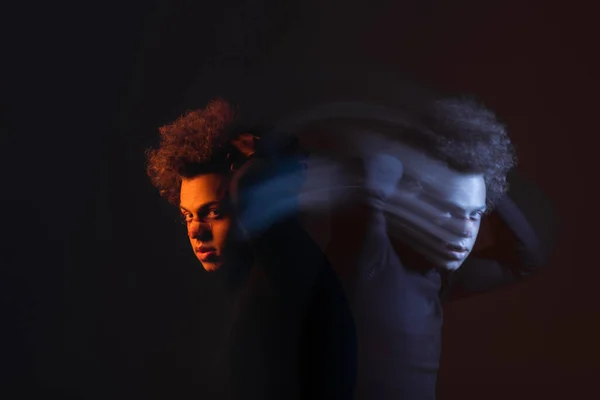 Double exposure of injured african american man with bipolar disorder looking at camera on dark background with orange and blue light — Stock Photo