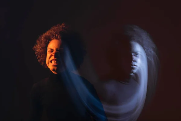 Doppia esposizione di uomo afroamericano con disturbo bipolare e viso ferito smorzante su sfondo nero con luce arancione e blu — Foto stock