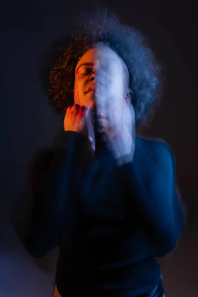 Подвійне опромінення пораненого афроамериканця з кривавим обличчям, що стоїть з закритими очима на чорному з червоним і синім світлом — стокове фото