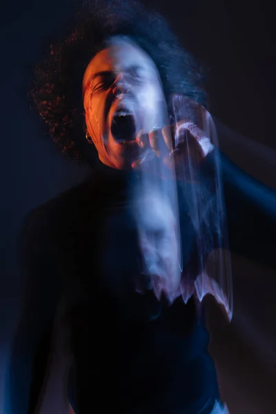 Double exposure of abused african american man with bipolar disorder and bleeding face screaming on black with orange and blue light - foto de stock