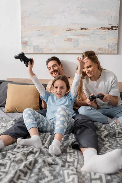 KYIV, UKRAINE - NOVEMBER 28, 2022: cheerful mother and excited child playing video game in bedroom — Stock Photo