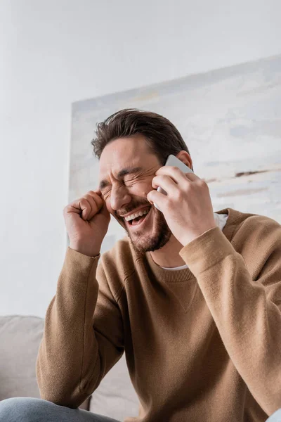 Happy man with closed eyes talking on smartphone at home — Stock Photo