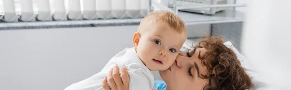 Woman with closed eyes kissing baby girl in hospital ward, banner — Stock Photo