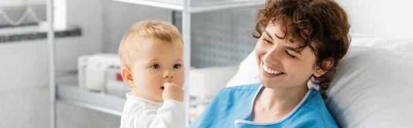 Little girl holding hand near mouth near happy mom in hospital ward, banner — Photo de stock