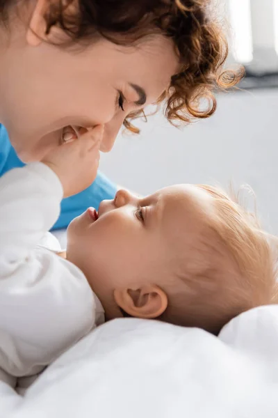 Side view of smiling toddler girl touching face of happy mother in hospital ward — Stock Photo