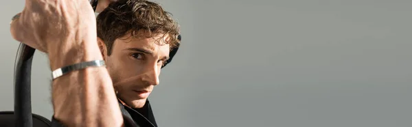 Портрет человека в металлическом браслете, смотрящего в камеру, позируя изолированно на сером, баннере — стоковое фото