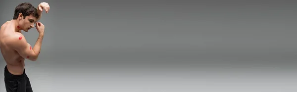 Side view of shirtless man with red kiss prints on sexy shirtless body on grey background, banner — Stock Photo