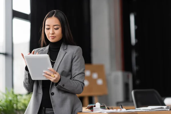 Young asian designer using digital tablet near working table in office — Stock Photo