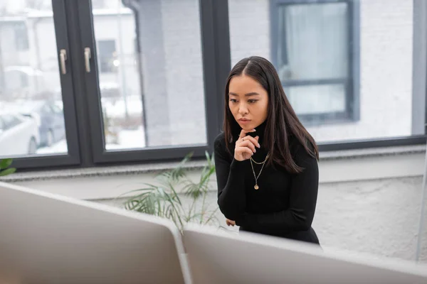 Concentrated asian designer looking at computer monitor in office — Stock Photo