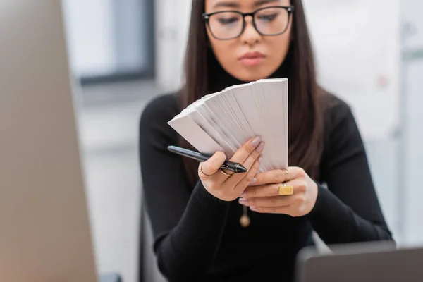 Blurred asian interior designer holding color samples near devices in office — Stock Photo