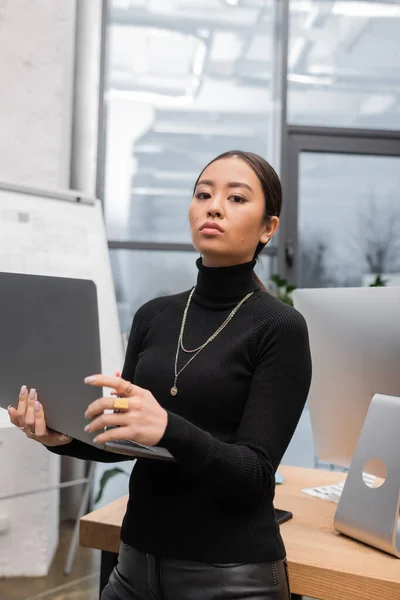 Portrait of asian interior designer in turtleneck holding laptop in studio — Stock Photo