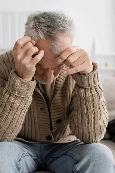 Aged man with parkinsonian syndrome and trembling hands sitting with bowed head at home — Fotografia de Stock