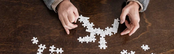 Top view of cropped man with parkinson disease and trembling hands combining jigsaw puzzle, banner — Stock Photo