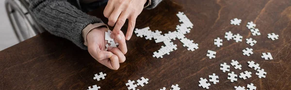 Cropped view of man with parkinson syndrome and tremor in hands holding elements of jigsaw puzzle, banner — Stock Photo