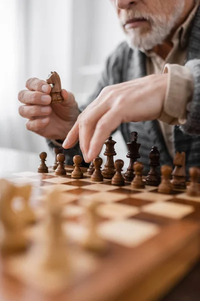 Partial view of senior man with alzheimer syndrome playing chess at home — Photo de stock