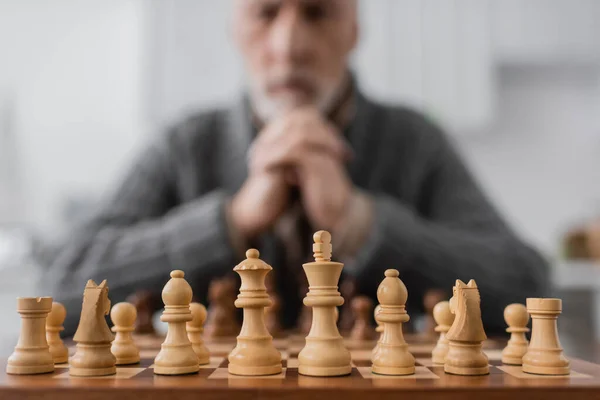 Selective focus of chessboard near senior man with alzheimer syndrome on blurred background — Photo de stock