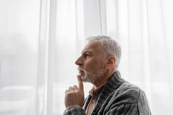 Side view of aged man with alzheimer disease looking away near window at home — Stock Photo