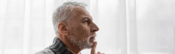 Profile of senior grey haired man with alzheimer disease touching chin while thinking at home, banner — Stock Photo