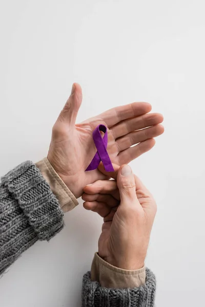 Top view of cropped senior man with alzheimer disease holding purple awareness ribbon on white background - foto de stock