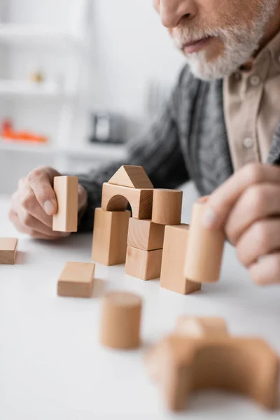 Partial view of man with alzheimer disease playing building blocks game on blurred foreground — Stock Photo