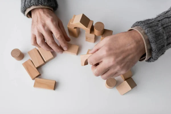 Top view of cropped man with alzheimer syndrome playing with wooden blocks on white table — Stock Photo