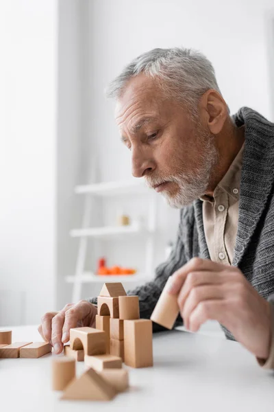 Side view of grey haired man with alzheimer syndrome playing therapy game at home — Stock Photo
